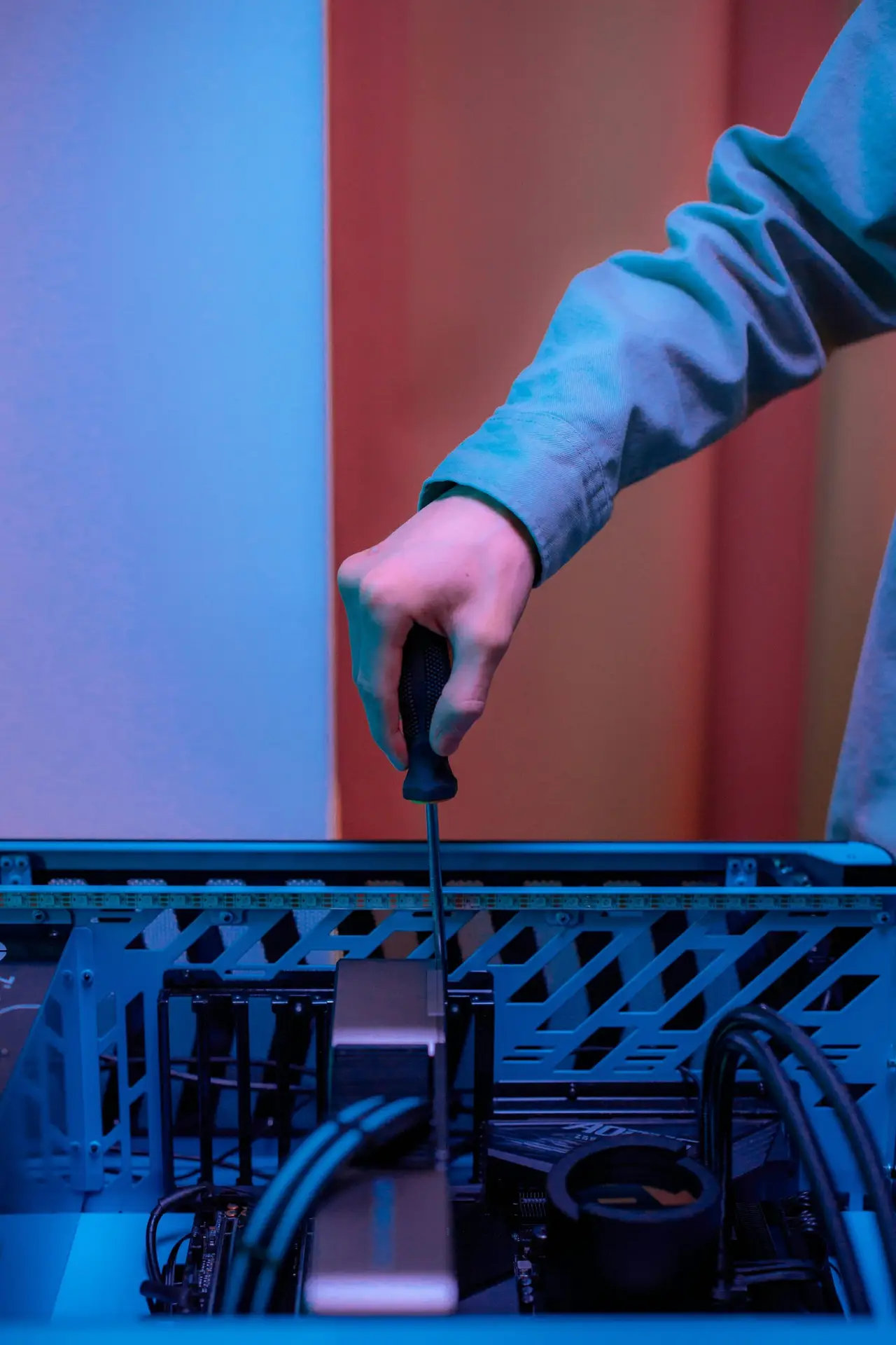 Close-up of hand using screwdriver inside PC tower, illustrating technology repair.